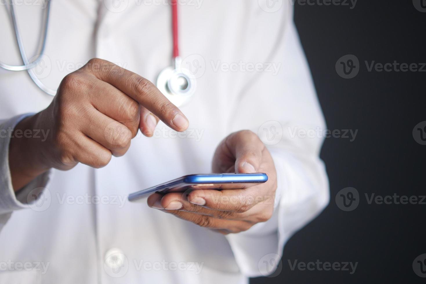 médico en bata blanca con un teléfono inteligente. foto