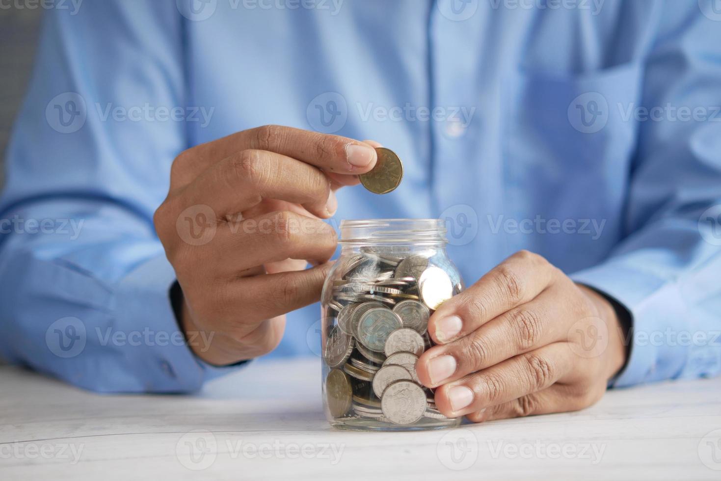 young man saving coins in a jar white sited photo