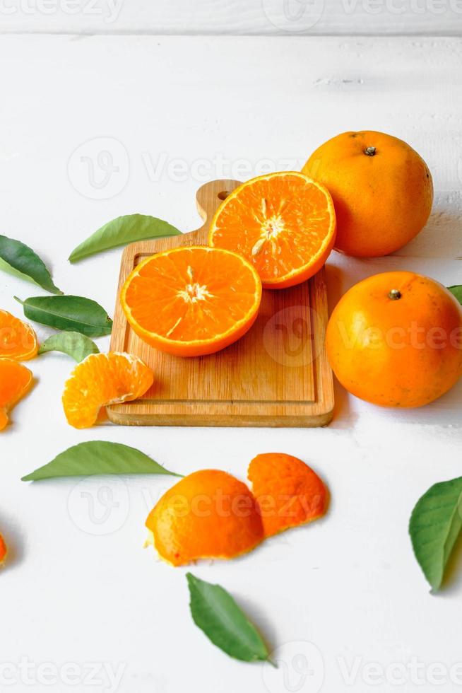 Fruta de naranja fresca cortada por la mitad sobre fondo de madera blanca foto