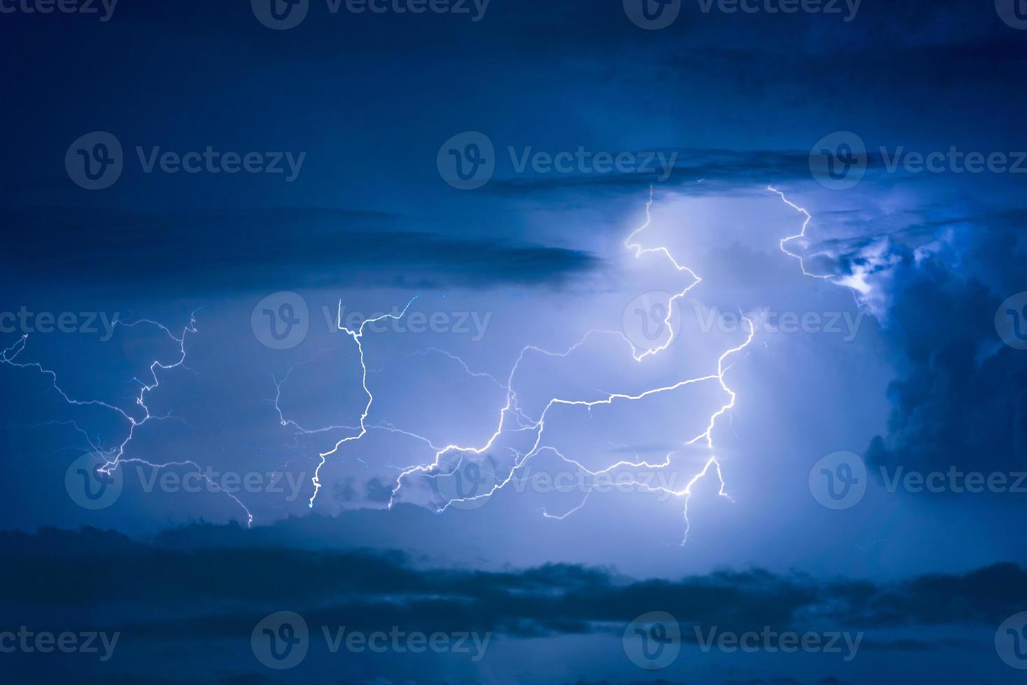 Thunder storm lightning strike on the dark cloudy sky background at night. photo