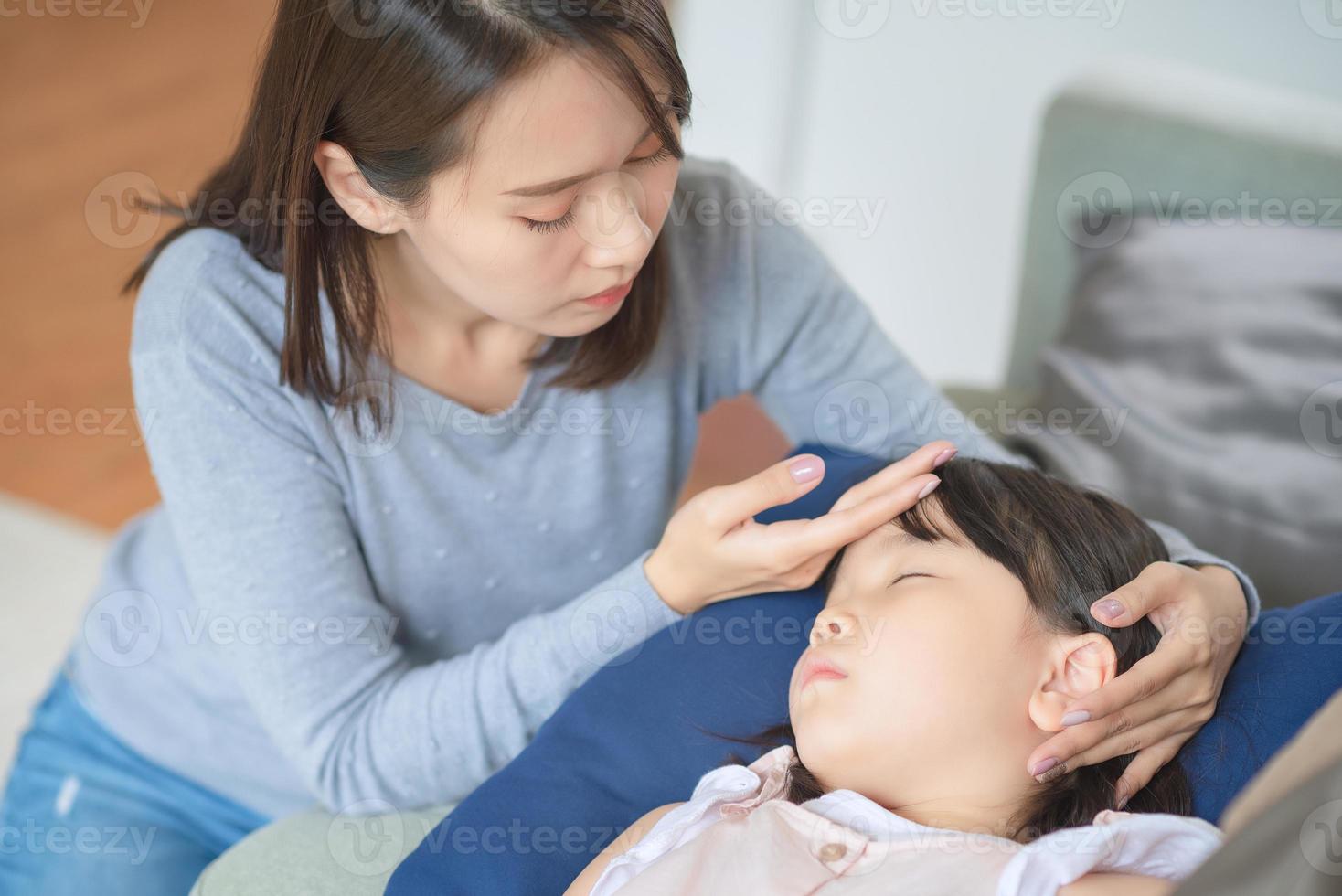 Asian mother take care of her kid which got fever and illness at home. photo