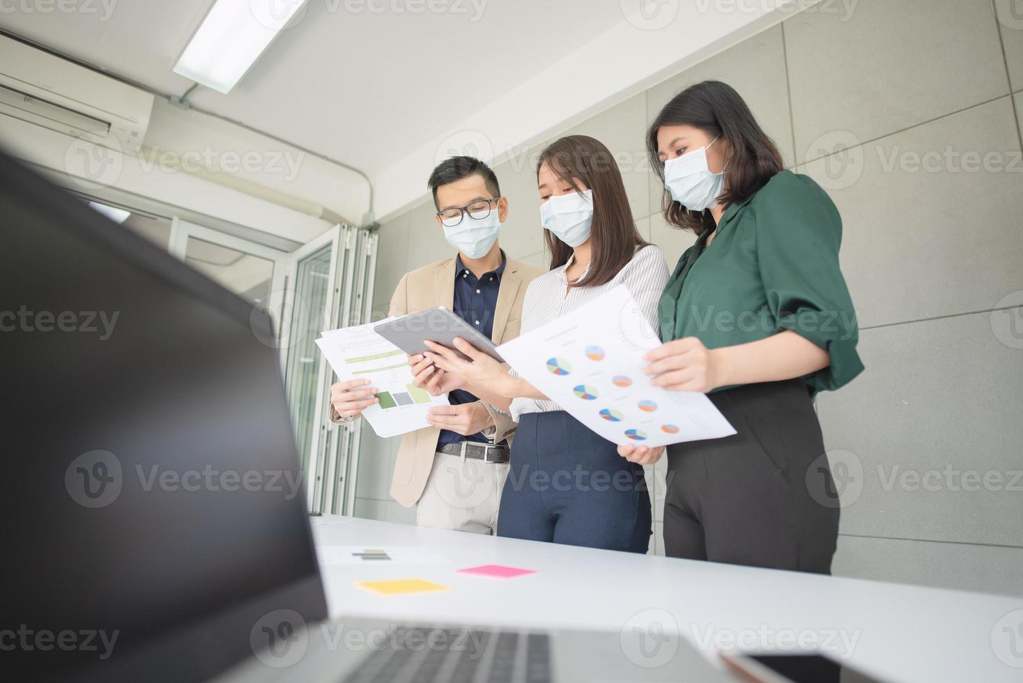 Empleados comerciales que usan máscara durante el trabajo en la oficina para mantener la higiene y seguir la política de la empresa. Prevención durante el período de epidemia de coronavirus o covid19. foto