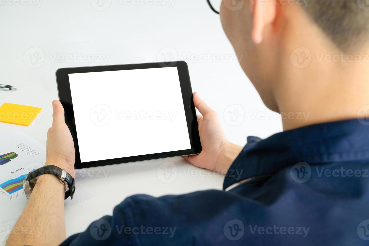 Vista posterior del hombre de negocios con tableta con pantalla en negro en la oficina. diseño fotográfico con espacio de copia para maquetas para videoconferencias con colegas a través de la tecnología de Internet en la oficina en casa. foto