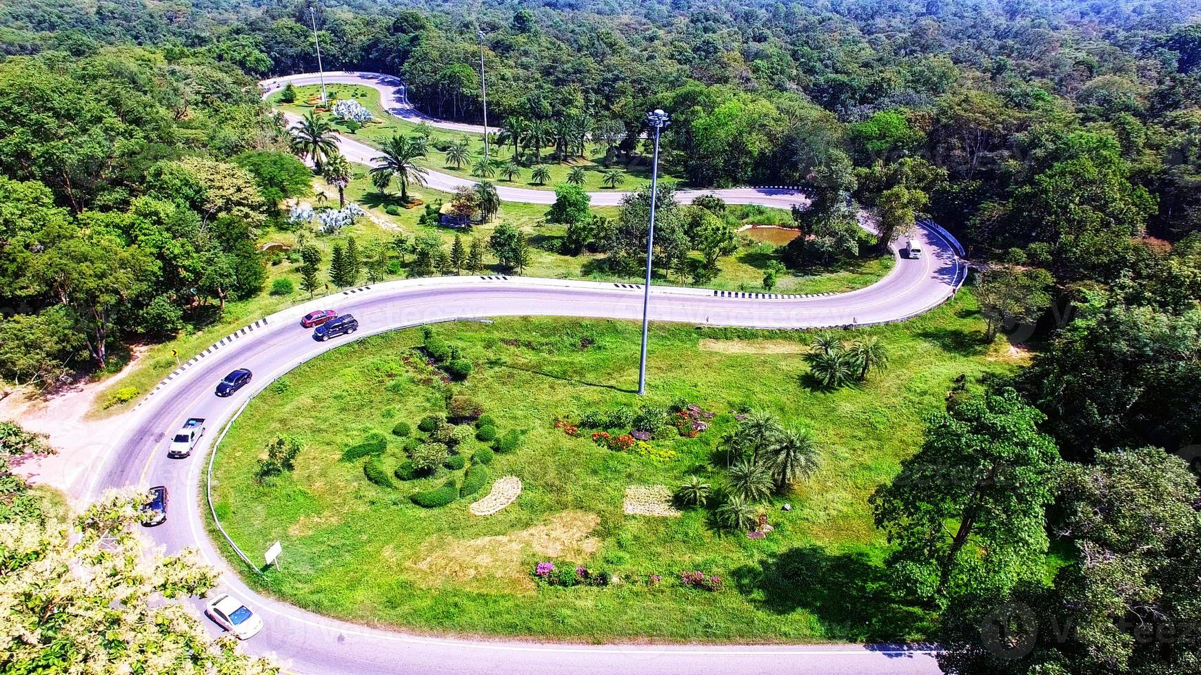 Aerial view from drone of cars are going through a curve road on the mountain with green forest. The transportation road across mountain. photo