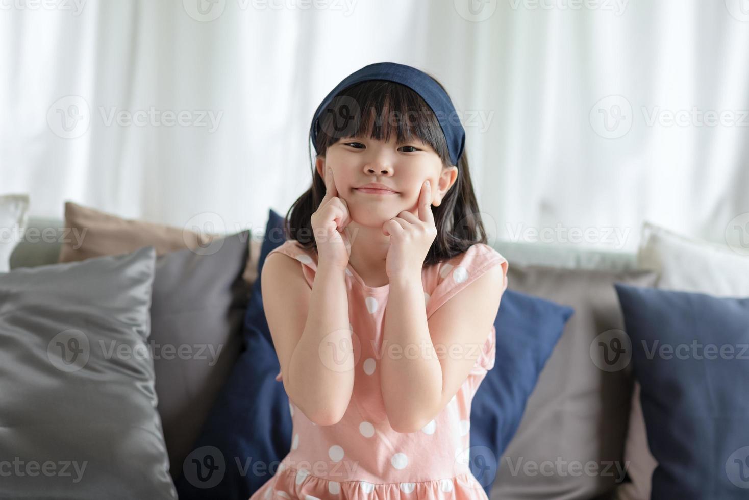 Retrato de niña linda asiática con sonrisa encantadora feliz en la sala de estar en casa. foto