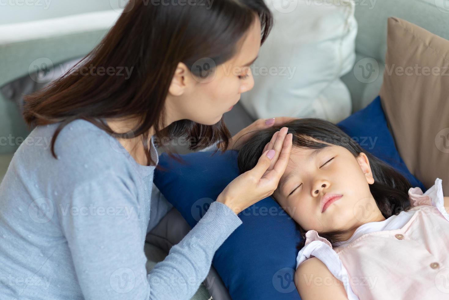 Asian mother take care of her kid which got fever and illness at home. photo