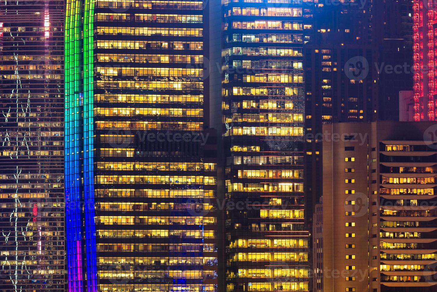 Close up colorido edificio moderno de gran altura vista desde el Kowloon durante la noche en Hong Kong. foto