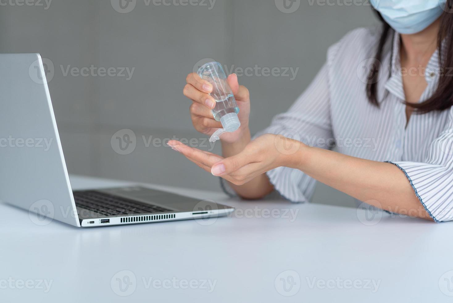 Business woman wearing mask and using personal sanitizer to cleaning her hand in office to keep hygiene.Preventive during the period of epidemic from coronavirus or covid19. photo