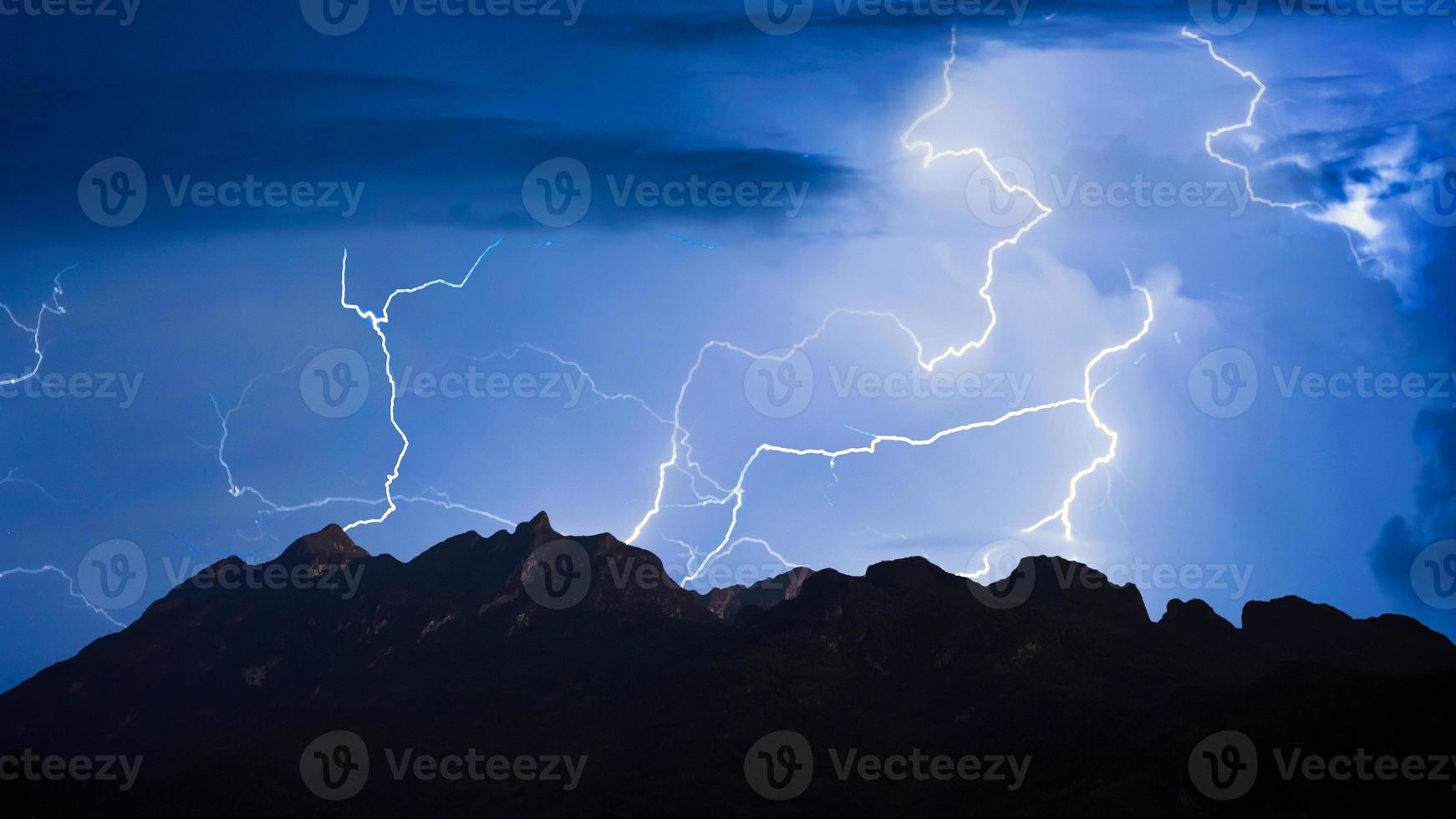 Panorama view of thunder storm lightning strike over mountain with dark cloudy sky background at night. photo