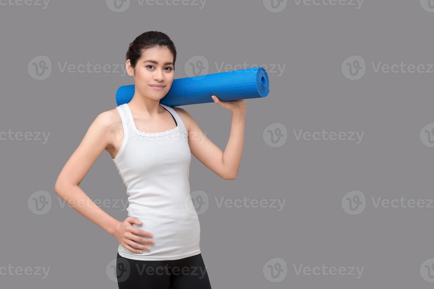 mujer asiática sosteniendo su estera de yoga en el gimnasio de deporte saludable. el yoga y la meditación tienen buenos beneficios para la salud. concepto de fotografía para el deporte de yoga y estilo de vida saludable foto