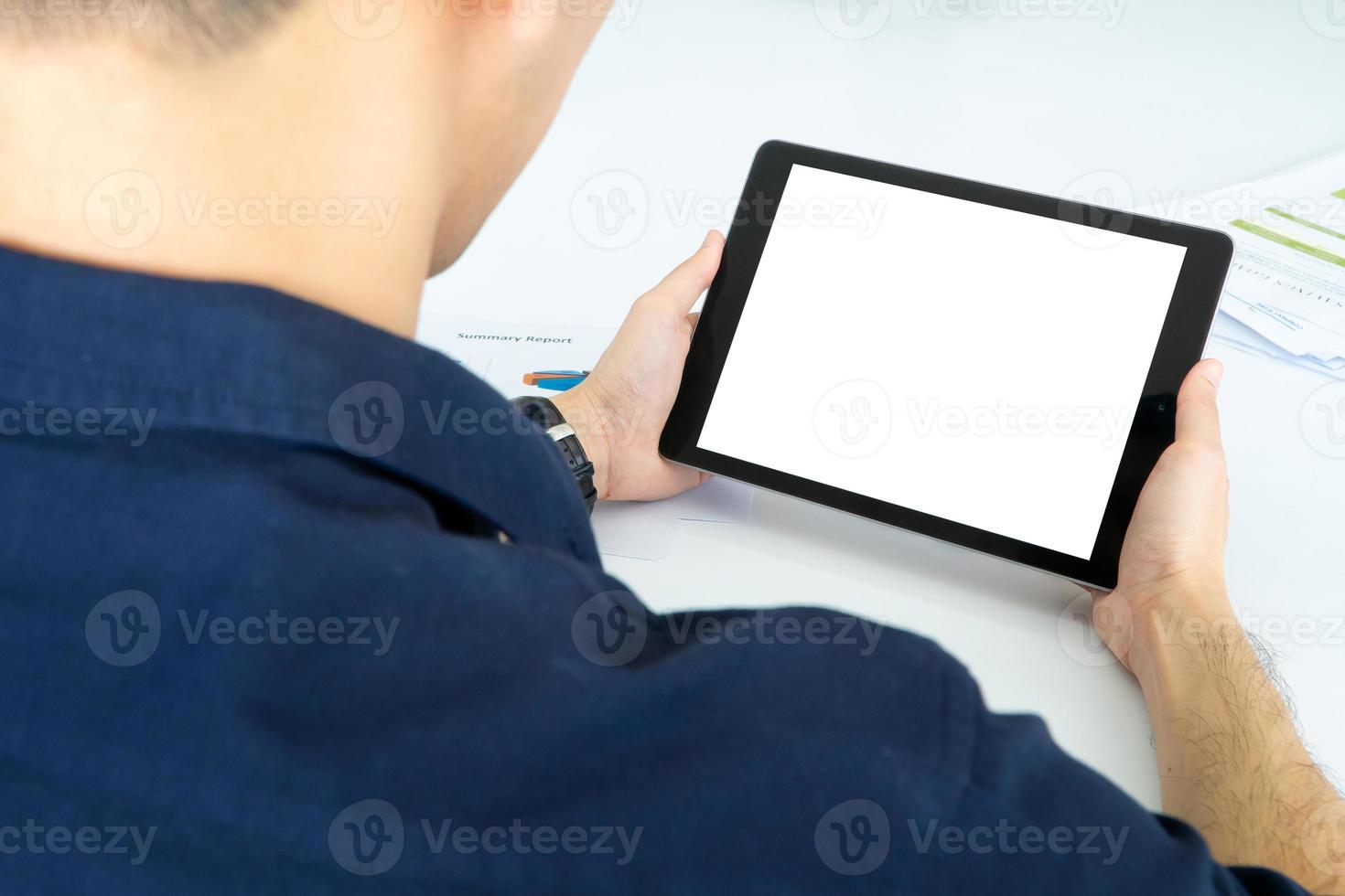 Back view of Business man using tablet with black screen in office. Photo design with copy space for mock up for video conferencing with colleagues via internet technology at home office.