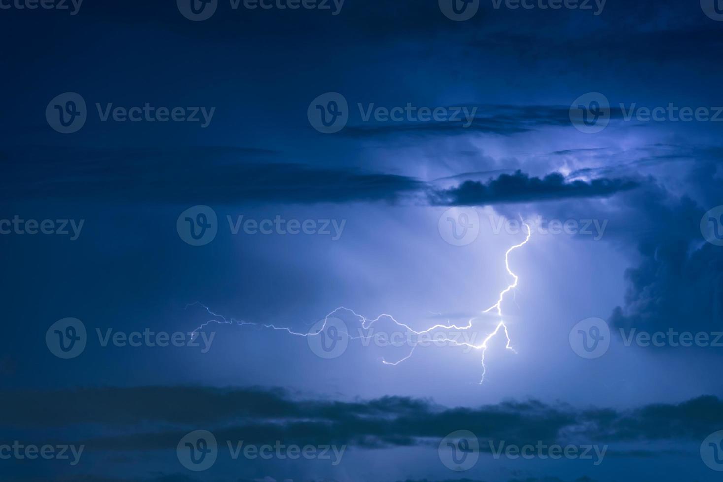 Thunder storm lightning strike on the dark cloudy sky background at night. photo