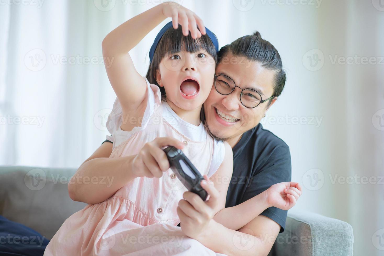 Asian Father and cute daughter enjoy and play console game on vacation at home photo