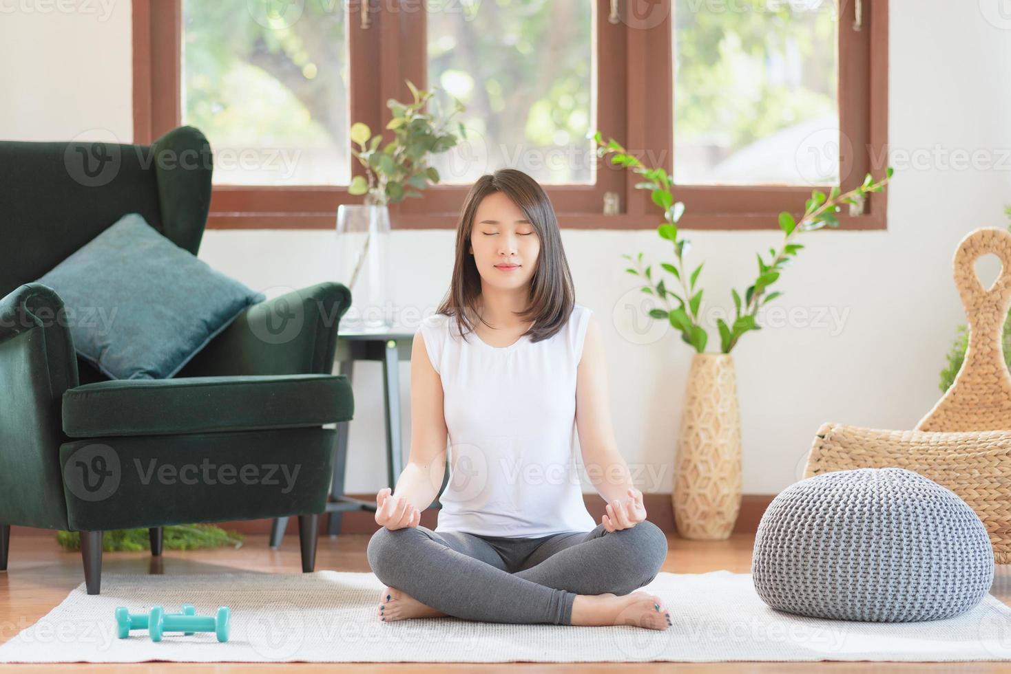 Beautiful asian woman keep calm and meditates while practicing yoga at home for healthy trend lifestyle photo