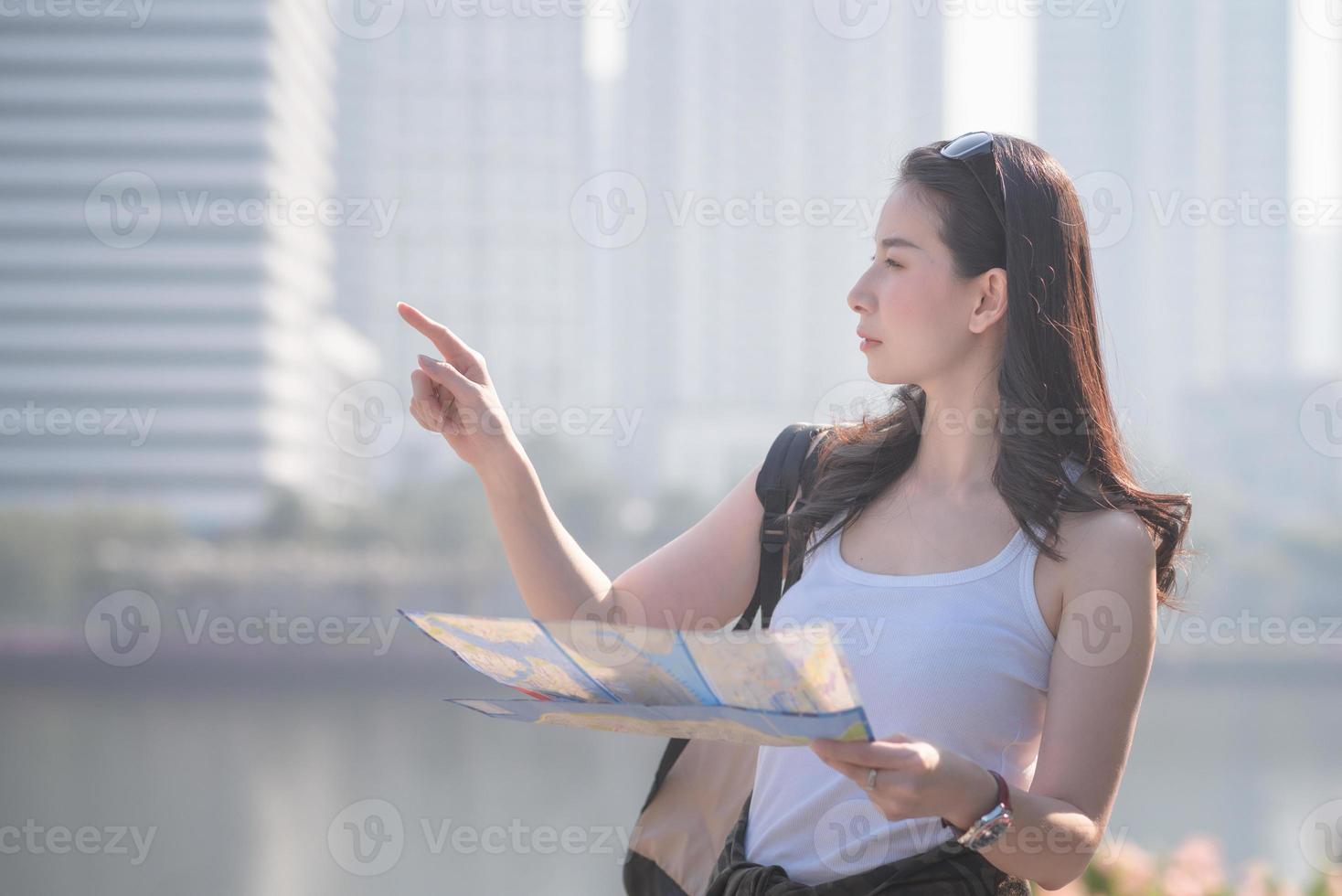 hermosa mujer asiática turista en solitario mirando el mapa en busca de turistas lugares de interés turístico. viajes de vacaciones en verano. foto