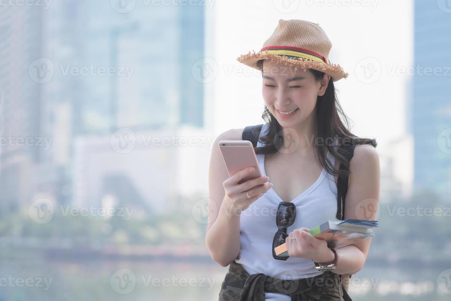 hermosa mujer asiática turista en solitario sonriendo y mirando el teléfono móvil para buscar turistas lugares turísticos. viajes de vacaciones en verano. foto