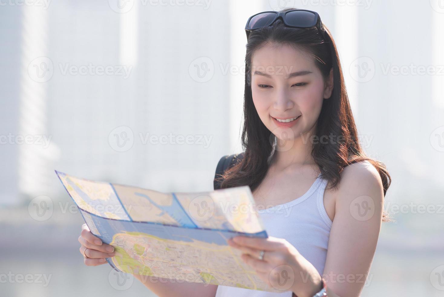 Beautiful asian solo tourist woman  looking at the map searching for tourists sightseeing spot. Vacation travel in summer. photo