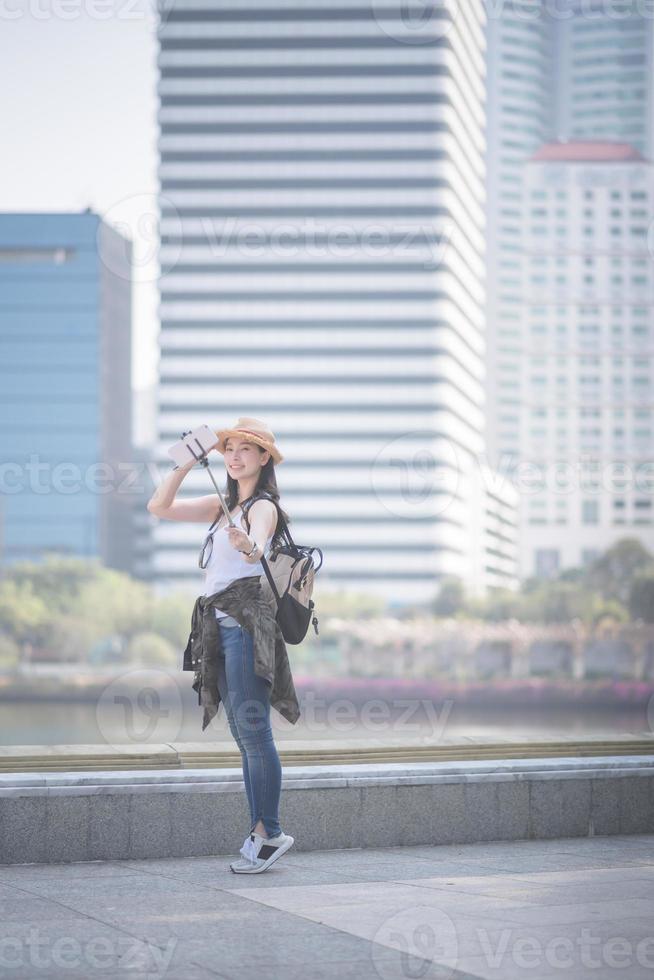 hermosa mujer asiática turista en solitario tomando selfies en un teléfono inteligente en el centro urbano de la ciudad. viajes de vacaciones en verano. foto