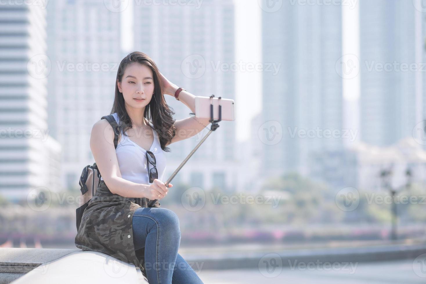 hermosa mujer turista asiática tomando autorretratos en un teléfono inteligente en el centro urbano de la ciudad. viajes de vacaciones en verano. foto