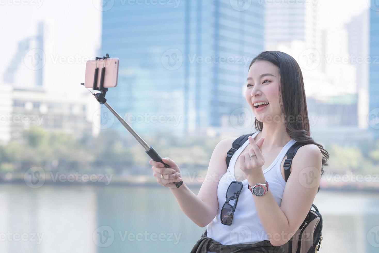 Beautiful asian woman enjoy using video call technology on a smartphone in urban city downtown. Vacation travel in summer. photo