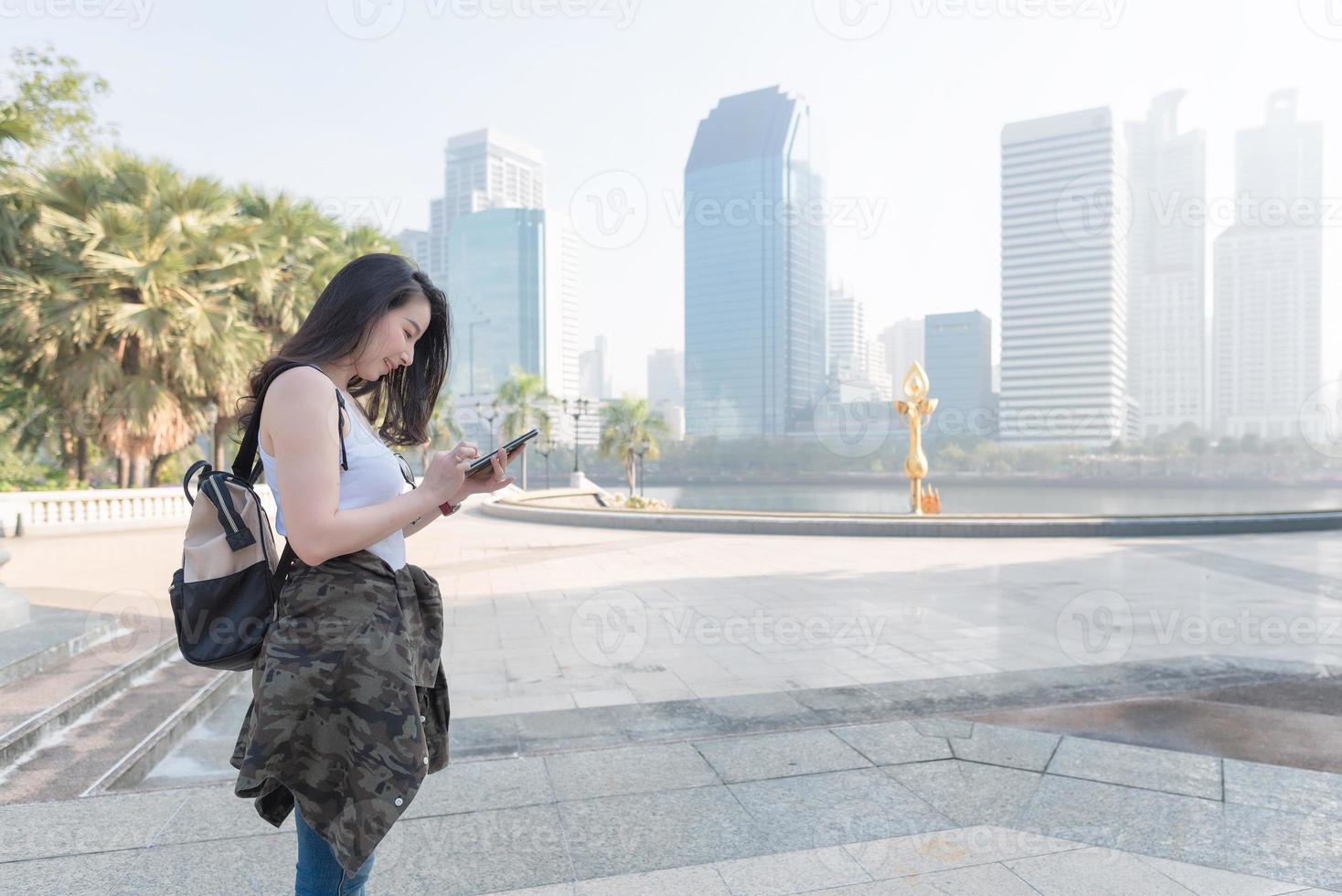 hermosa mujer turista asiática mirando el teléfono móvil para buscar la ubicación del hito. viajes de vacaciones en verano foto