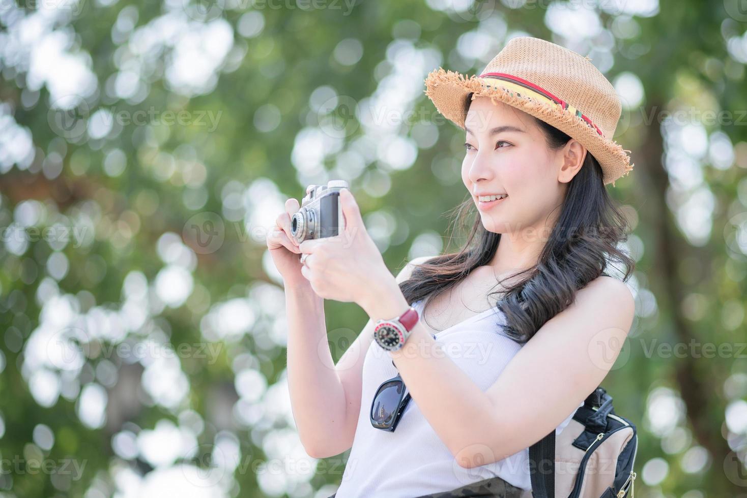 Beautiful asian tourist woman enjoy taking photo by retro camera at tourist sightseeing spot. Vacation travel in summer.