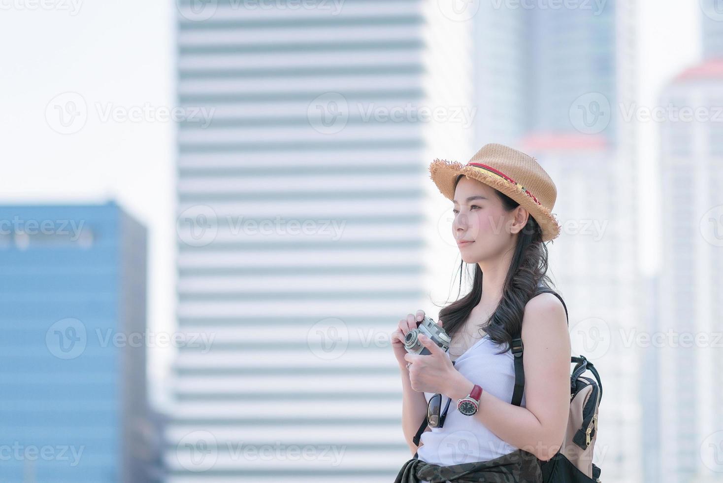 Hermosa mujer turista asiática disfruta tomando fotos con una cámara retro en un lugar turístico. viajes de vacaciones en verano.