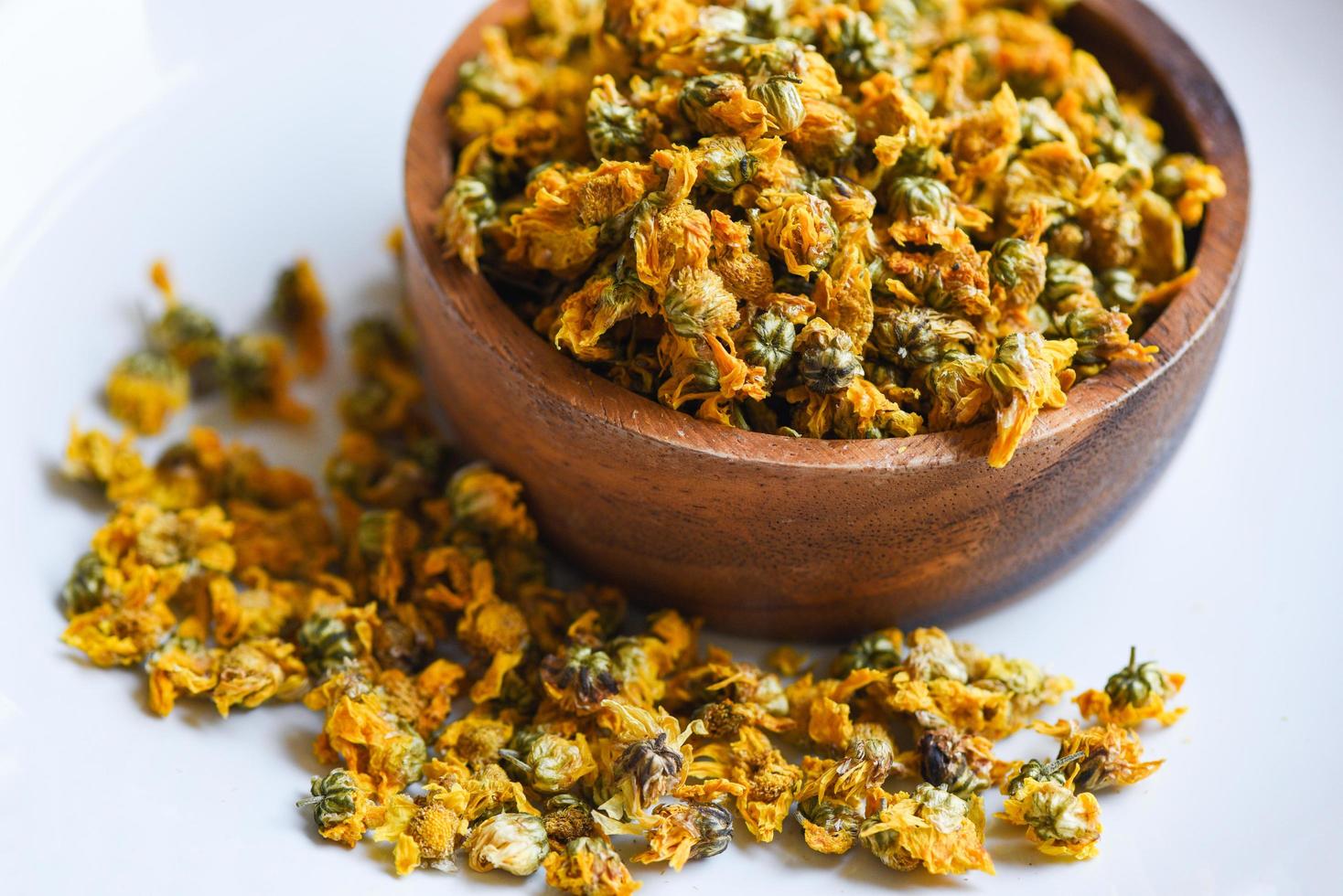 Dried chrysanthemum buds for herbal tea on wooden bowl, dry chrysanthemum flower yellow photo