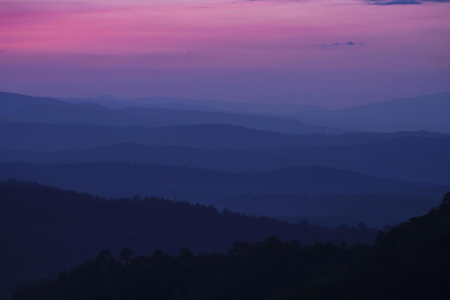 naturaleza paisaje fondo hermosa vista de la niebla de la mañana llenando los valles de colinas suaves capa de cordillera bosque azul oscuro amanecer y atardecer en montañas con cielo púrpura dramático foto