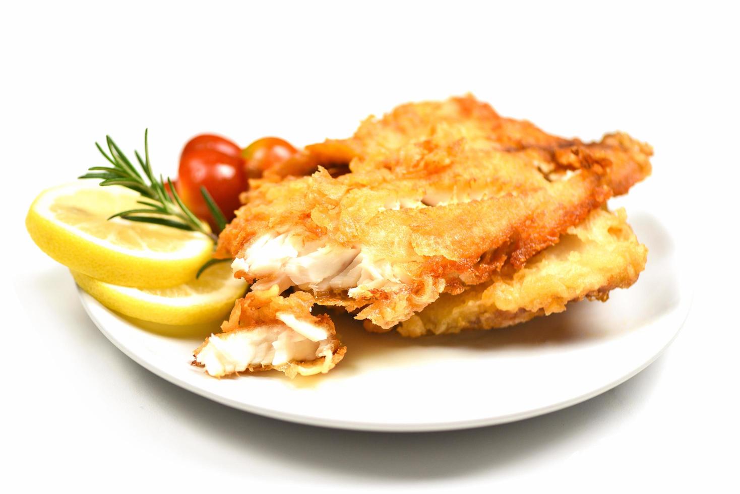 Filete de pescado frito en rodajas para bistec o ensalada cocinar alimentos con hierbas especias romero y limón - filete de tilapia pescado crujiente servido en un plato blanco foto