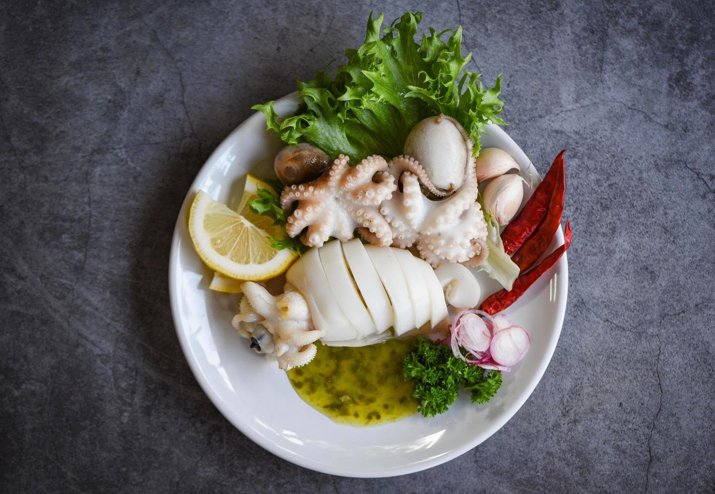 Alimentos cocidos calamares pulpo o sepia en el restaurante de mariscos - ensalada de calamar especias salsa de chile ajo limón sobre fondo de placa blanca foto