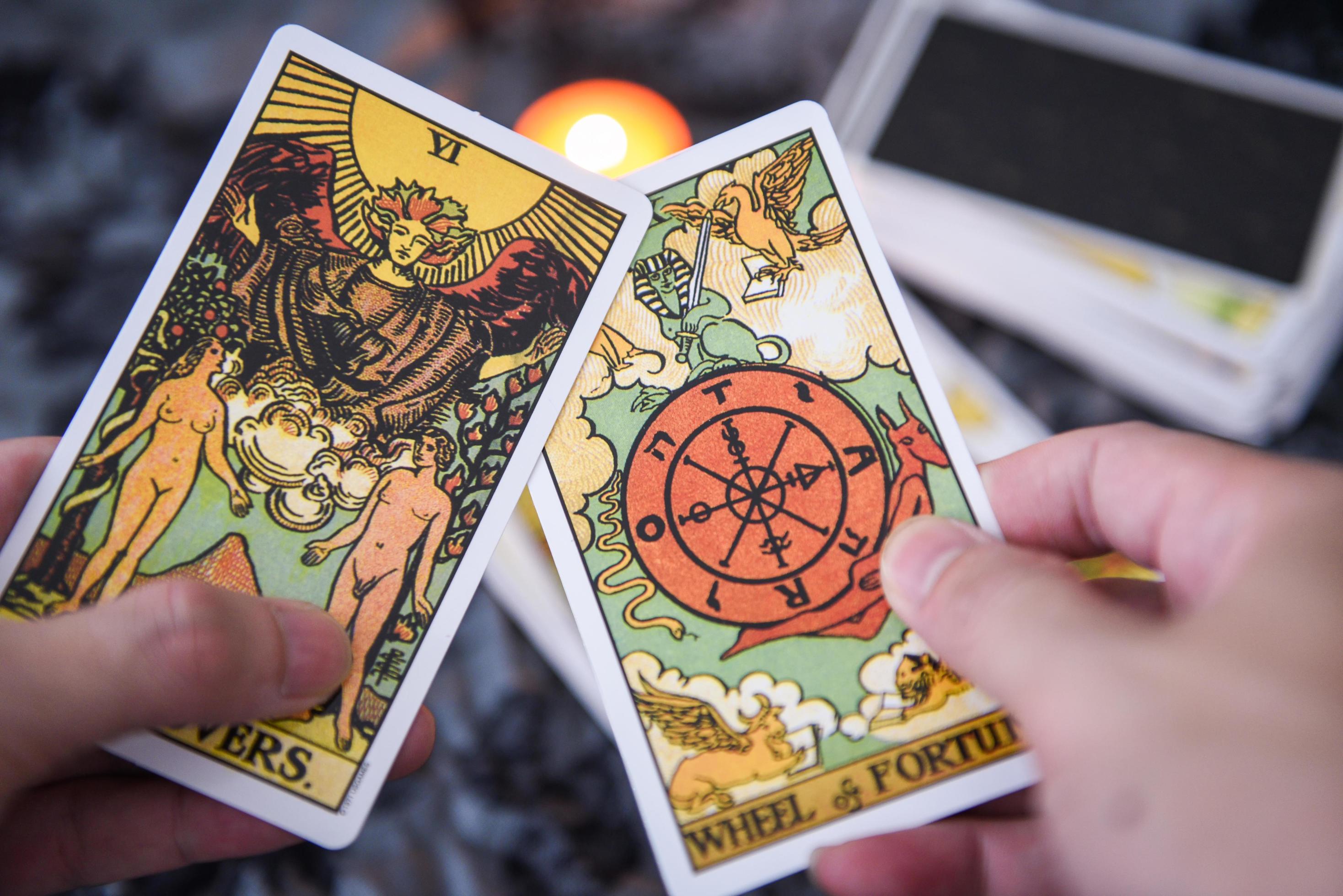 Fortune teller using tarot cards reading future by candlelight on dark