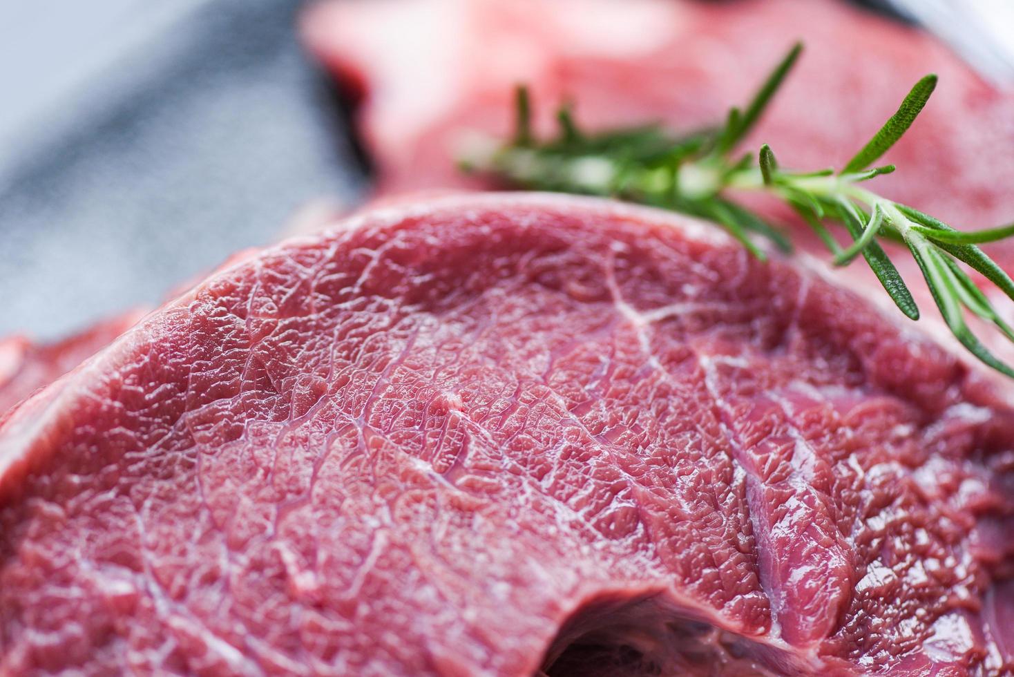 Carne de res fresca proteína animal en rodajas cerca de detalles carne de vacuno cruda textura de fondo carne fresca con romero foto
