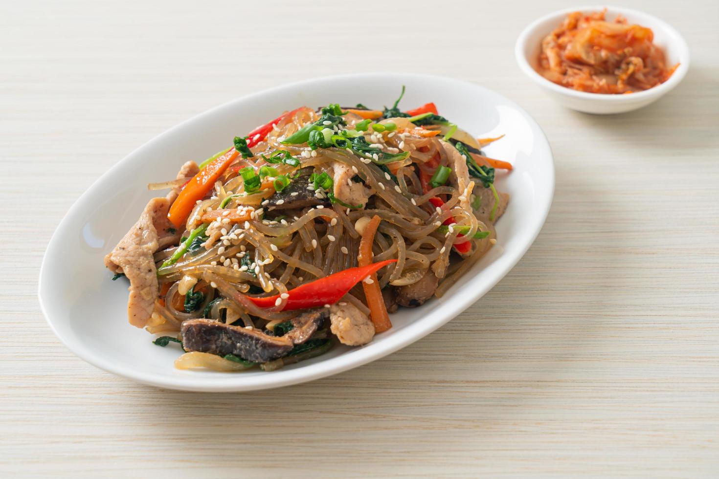 japchae o fideos de fideos coreanos salteados con verduras y carne de cerdo con sésamo blanco foto