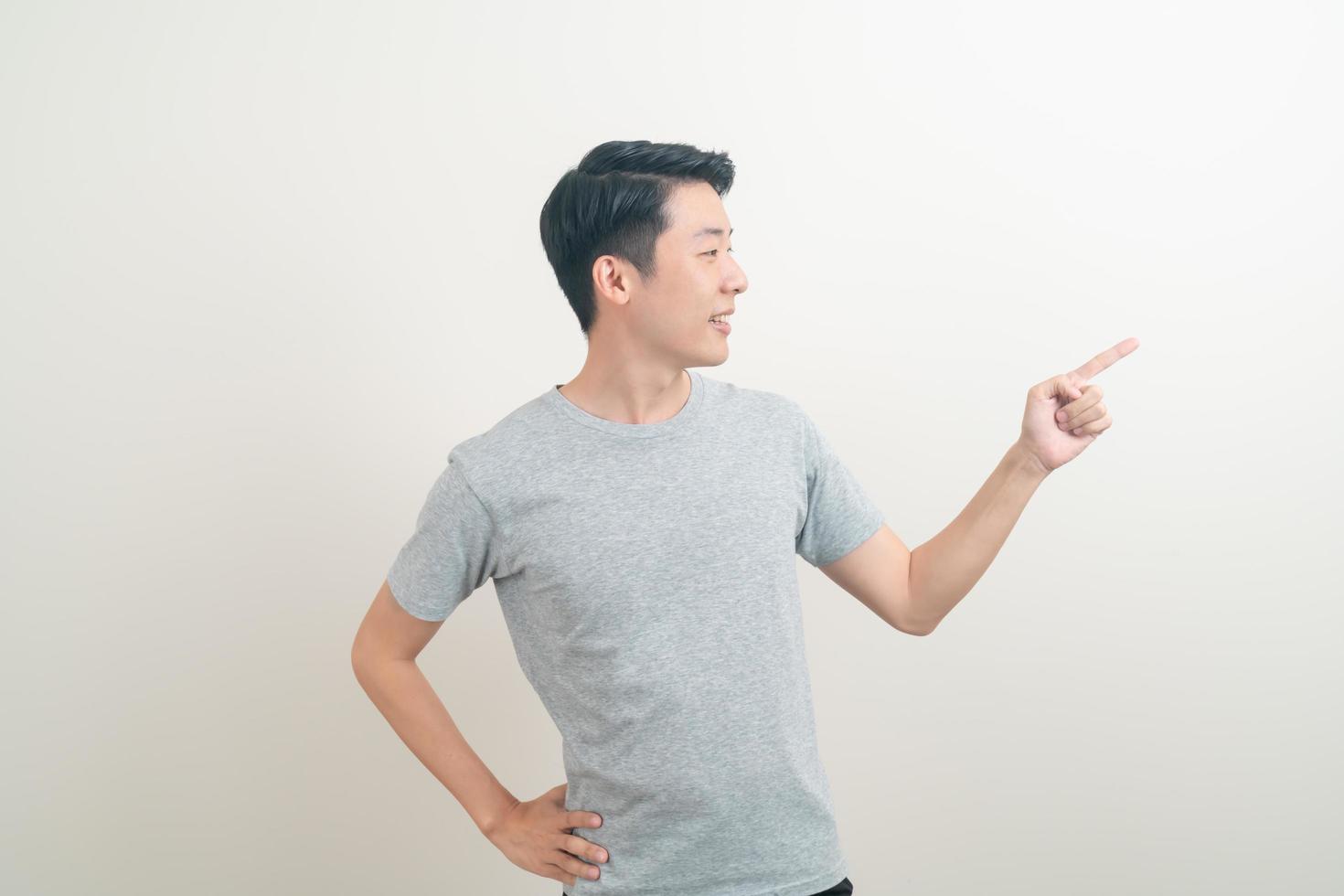 Hombre asiático con la mano apuntando o presentando sobre fondo blanco. foto