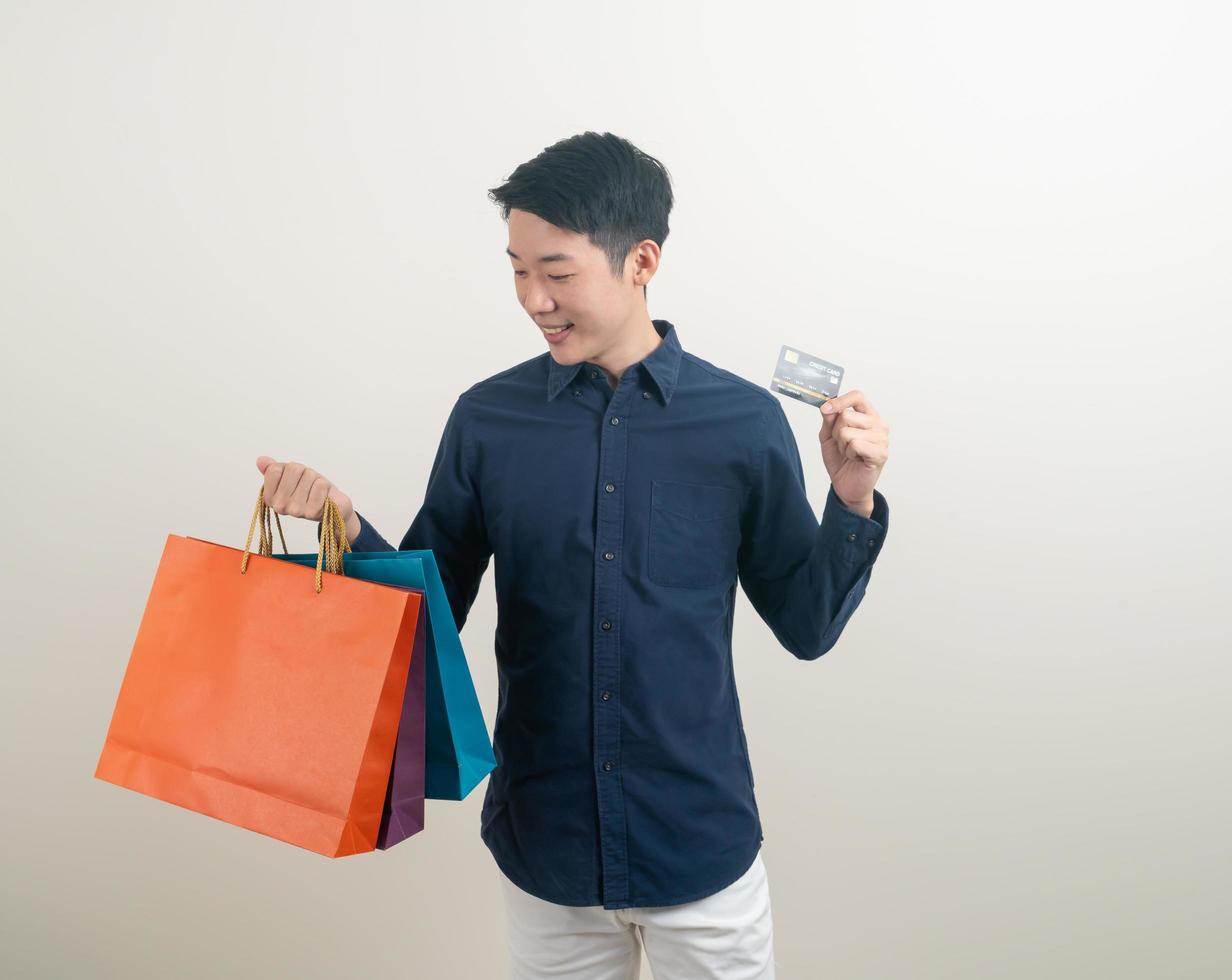 retrato, joven, asiático, hombre, tenencia, tarjeta de crédito, y, bolsa de compras foto