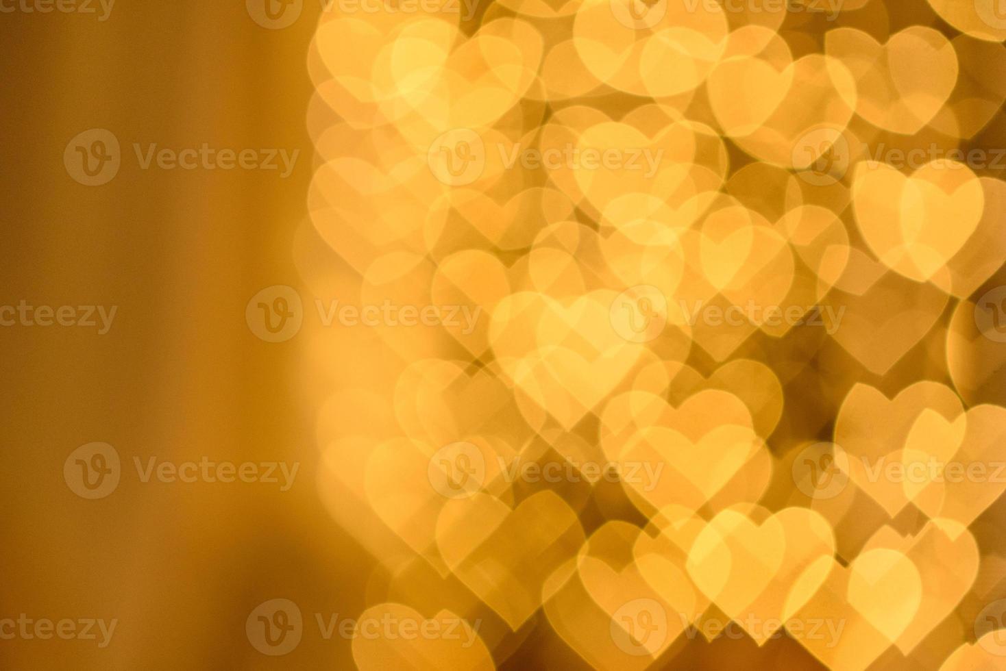 A lot of golden lights in the shape of hearts in the defocus on a dark background photo