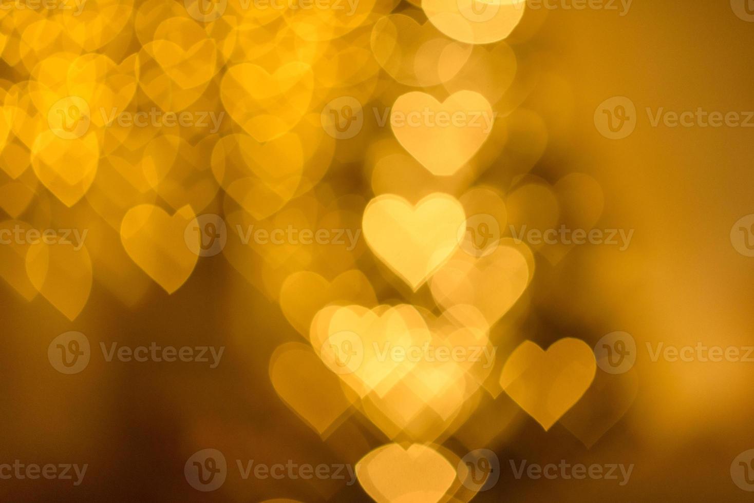 A lot of golden lights in the shape of hearts in the defocus on a dark background photo