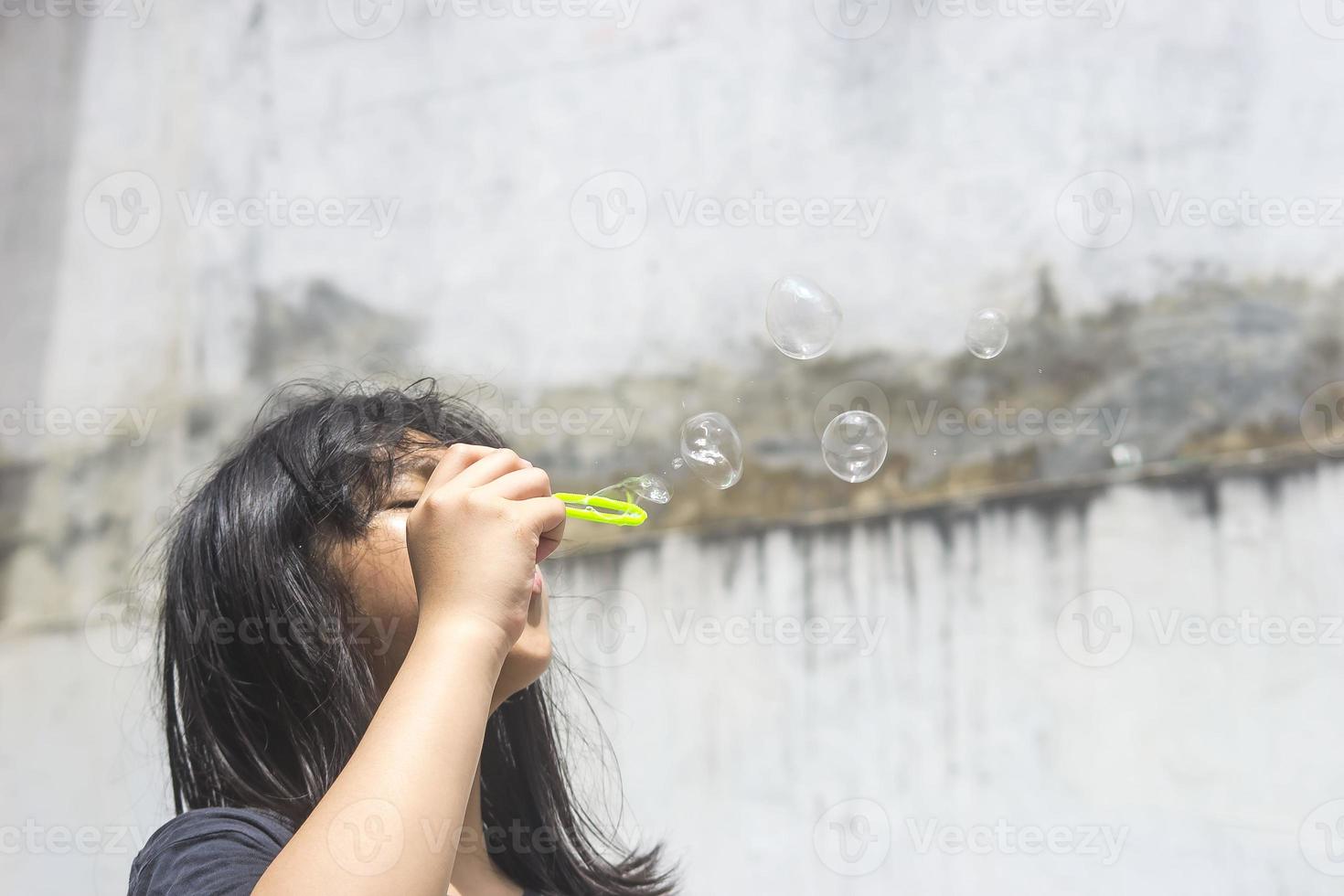 A girl holding a bubble maker and blowing them out. photo