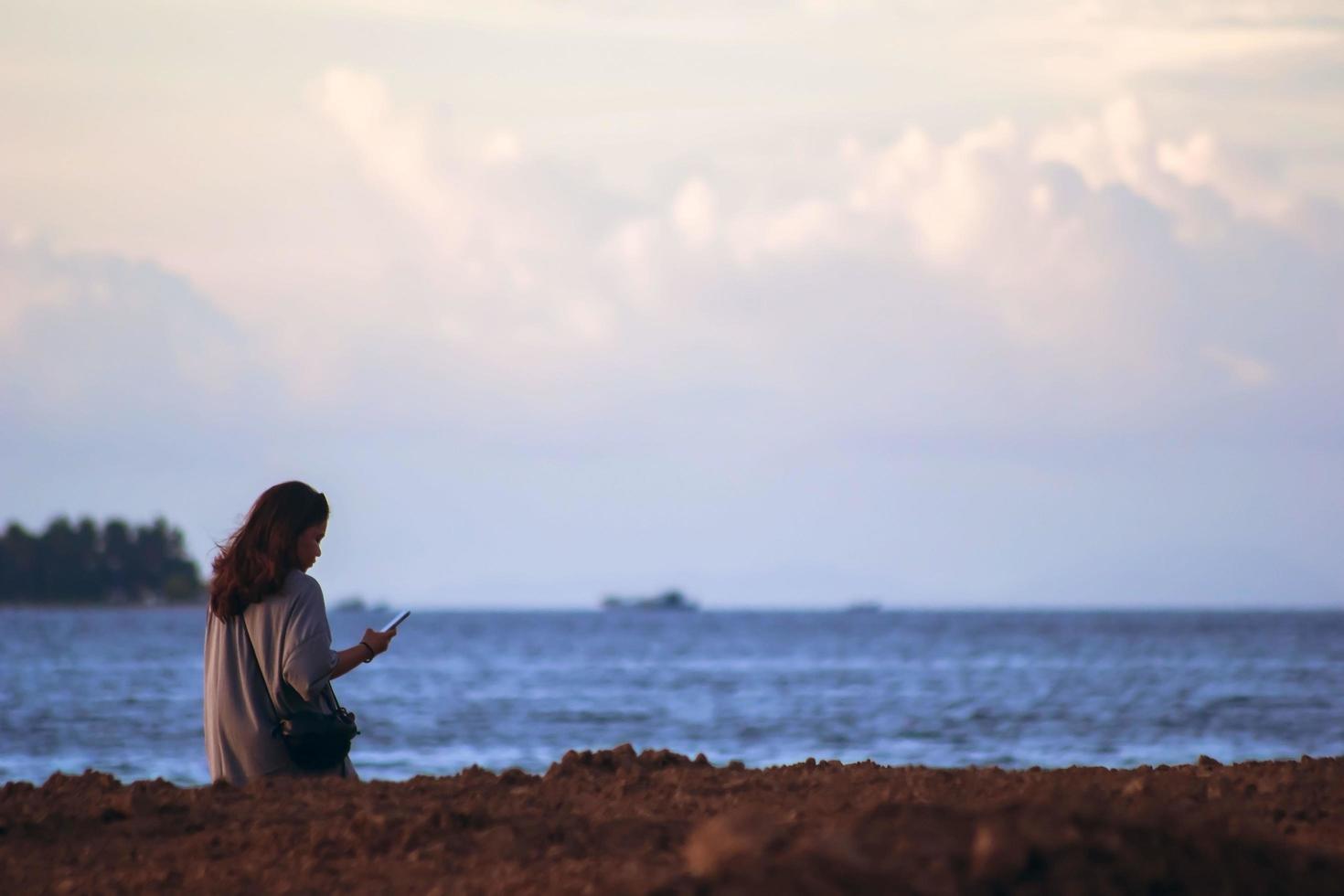 Sorong, West Papua, Indonesia, November 19th 2021. A girl alone on the beach taking self-portrait with smartphone. Me time. photo