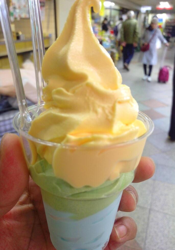 helado de vainilla y patrón de postre helado sabor fresa en taza negra mano sujetando la madera. foto