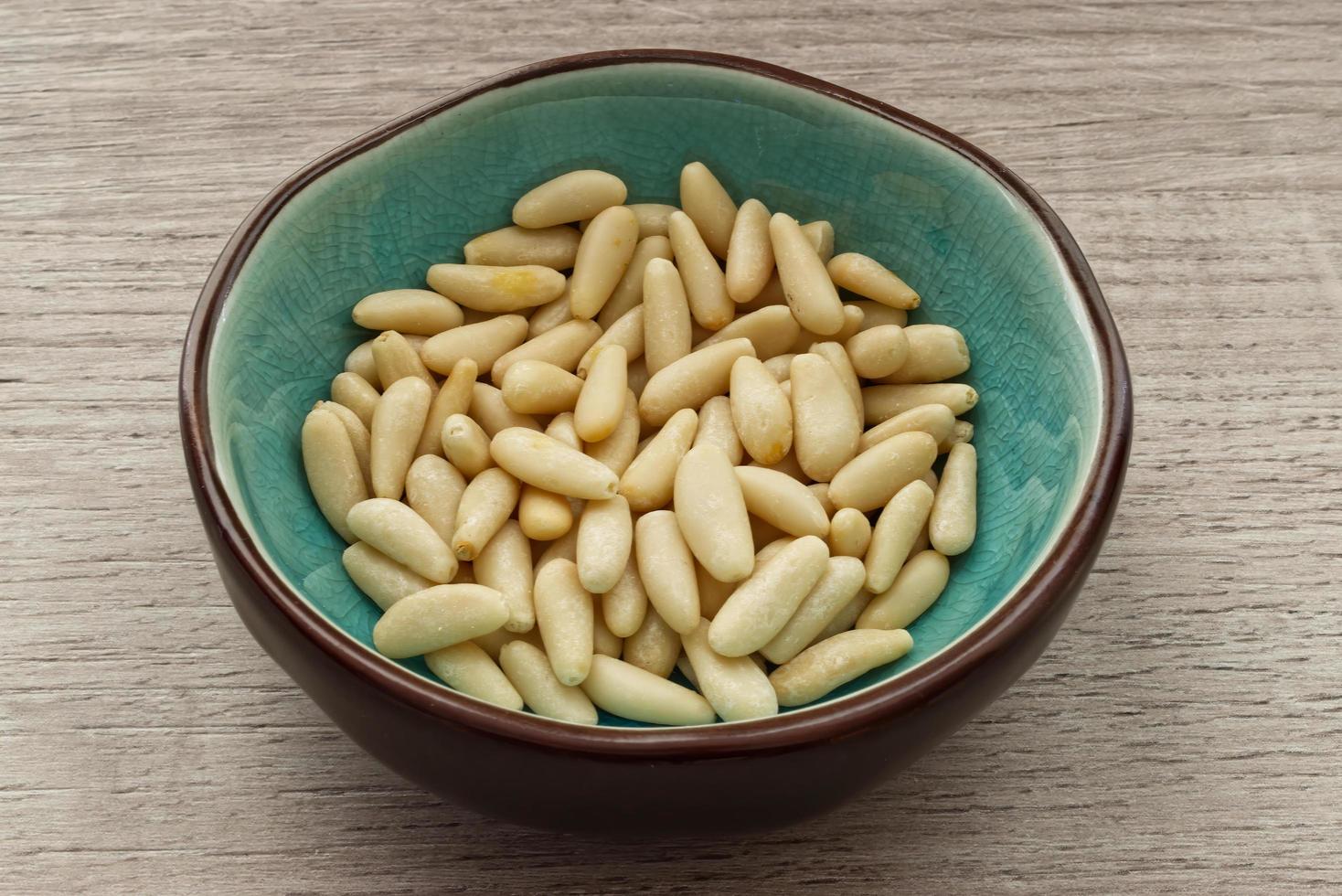 Pine nuts in a bowl isolated on wooden background photo