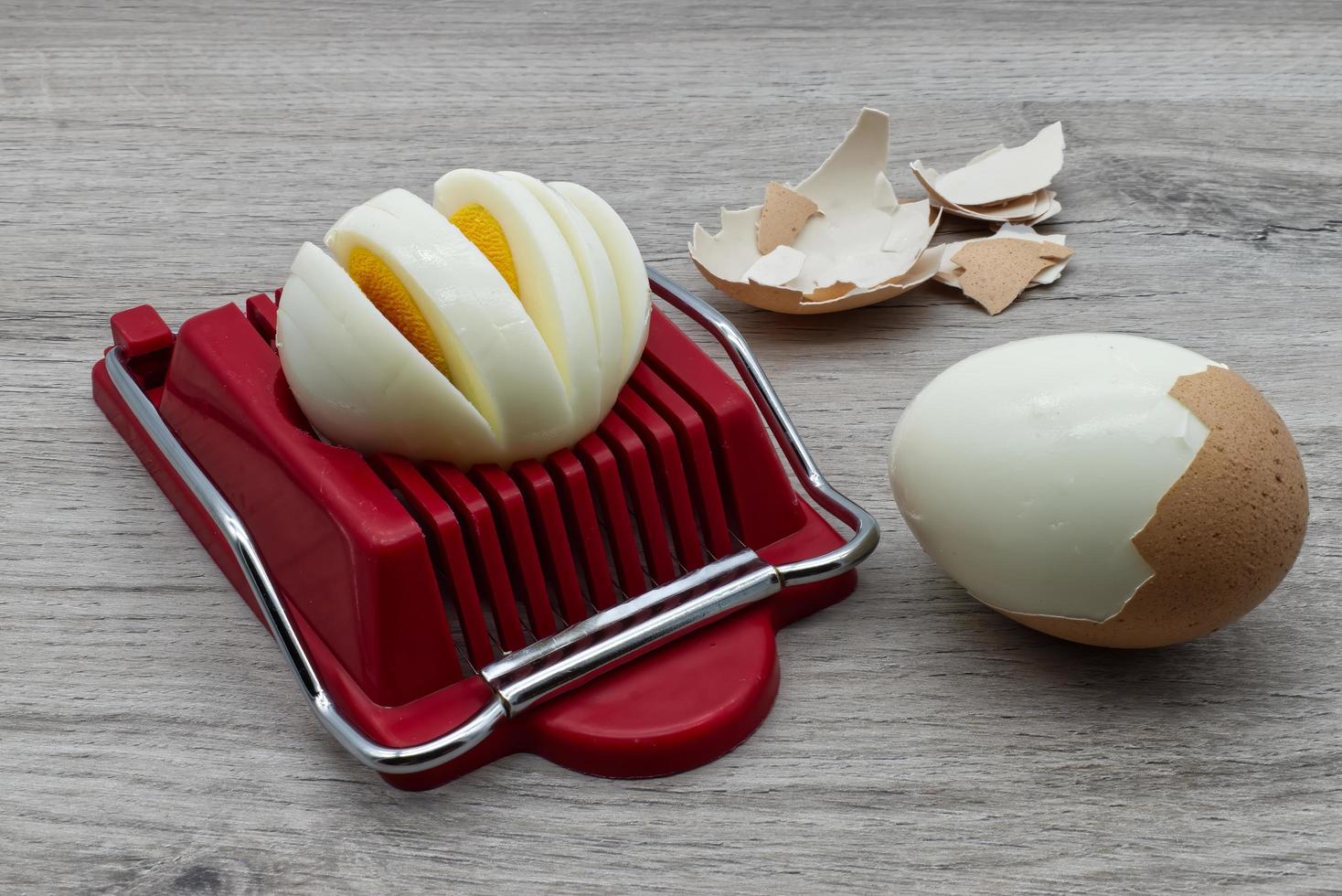 Egg slicer tool with boiled egg on wooden table photo