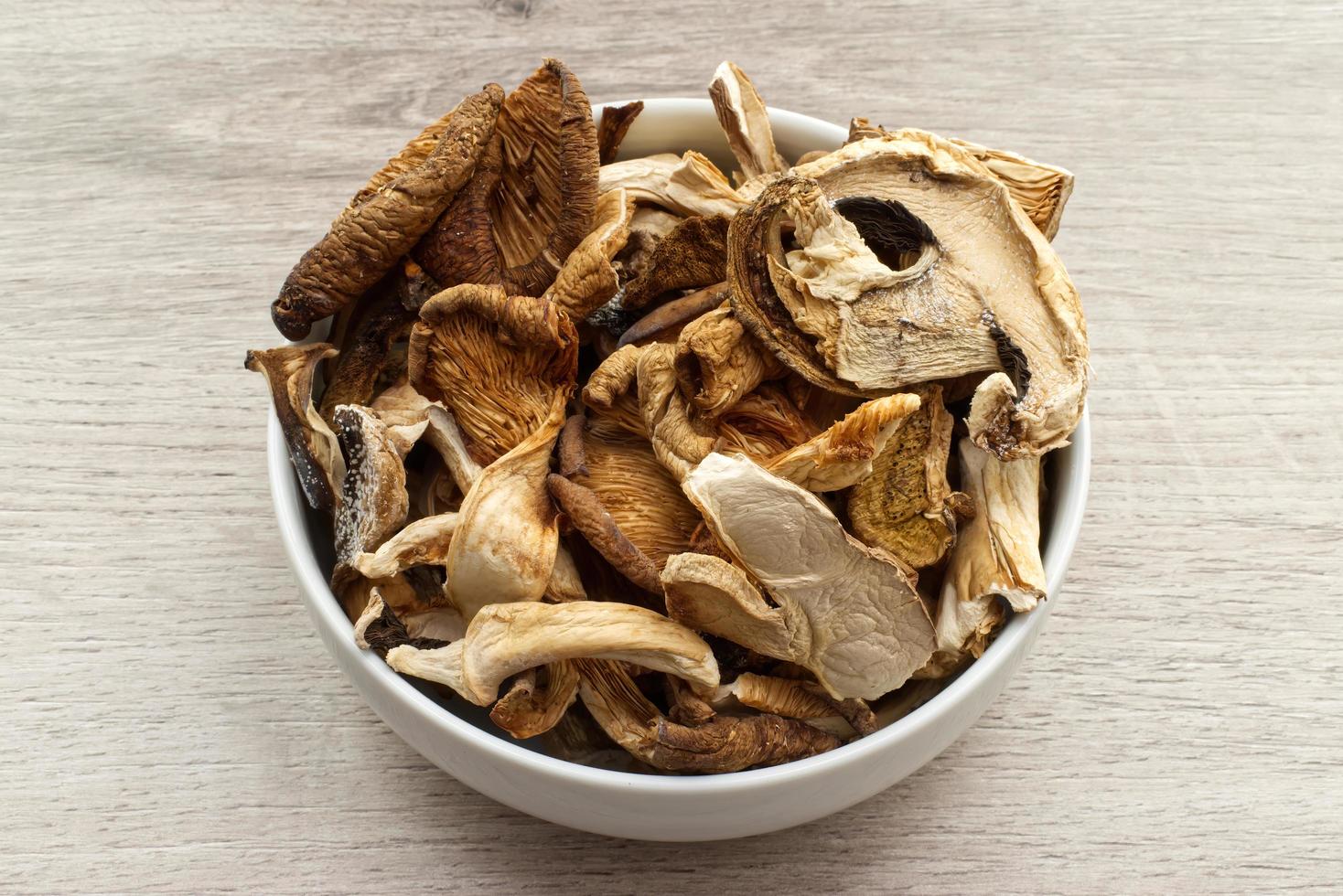 Dried mushrooms in a bowl isolated on wooden background photo