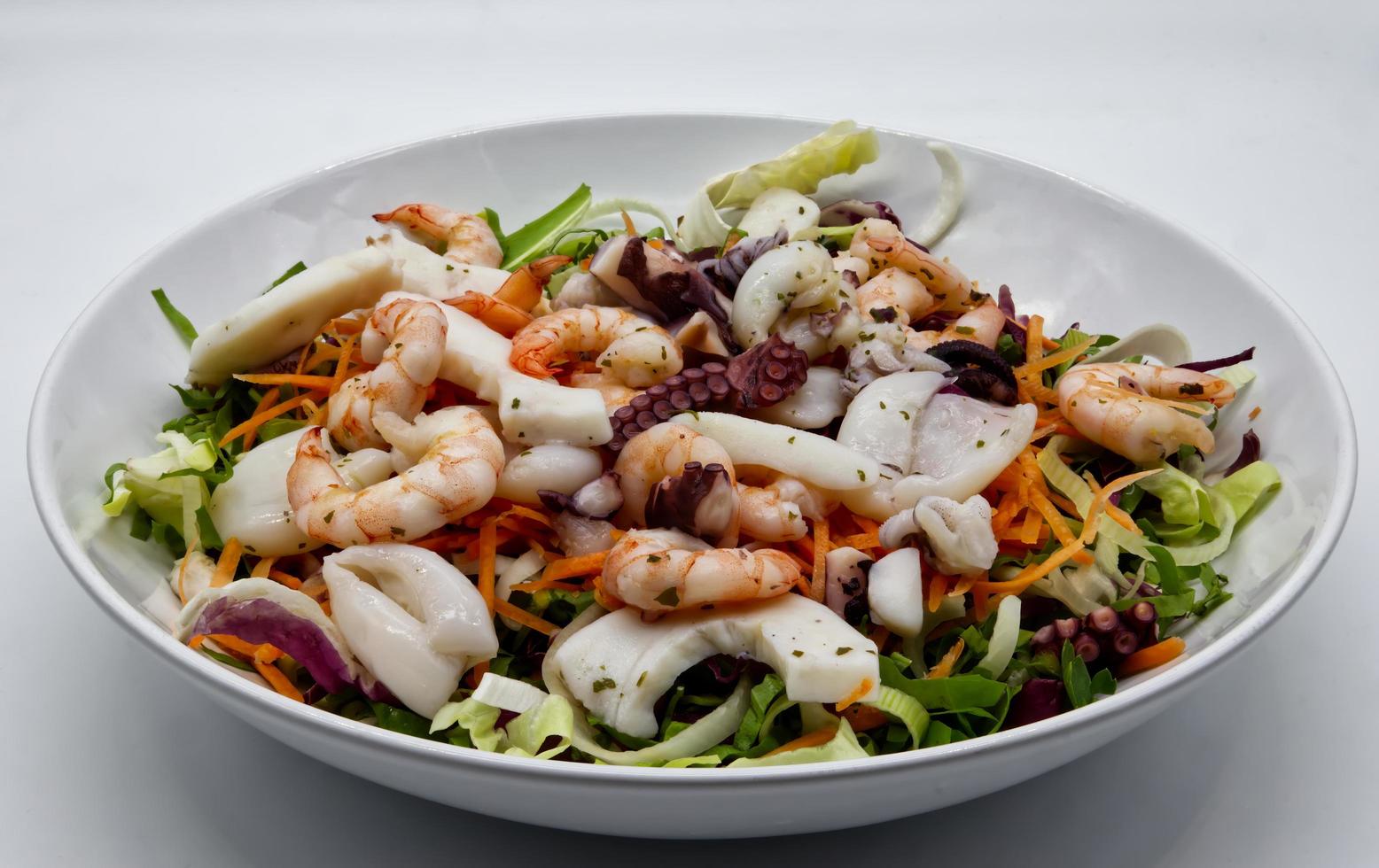 Fresh salad from seafood, octopus, cuttlefish, shrimp. Sea salad on white dish. photo