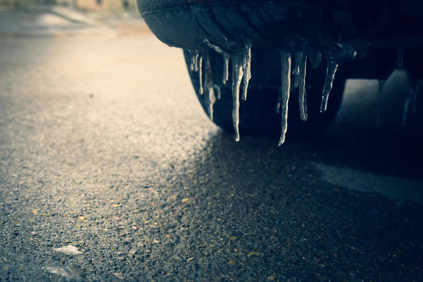 Close up view icicles car bumber with tires on frosty road concept. Slippery road conditions concept photo