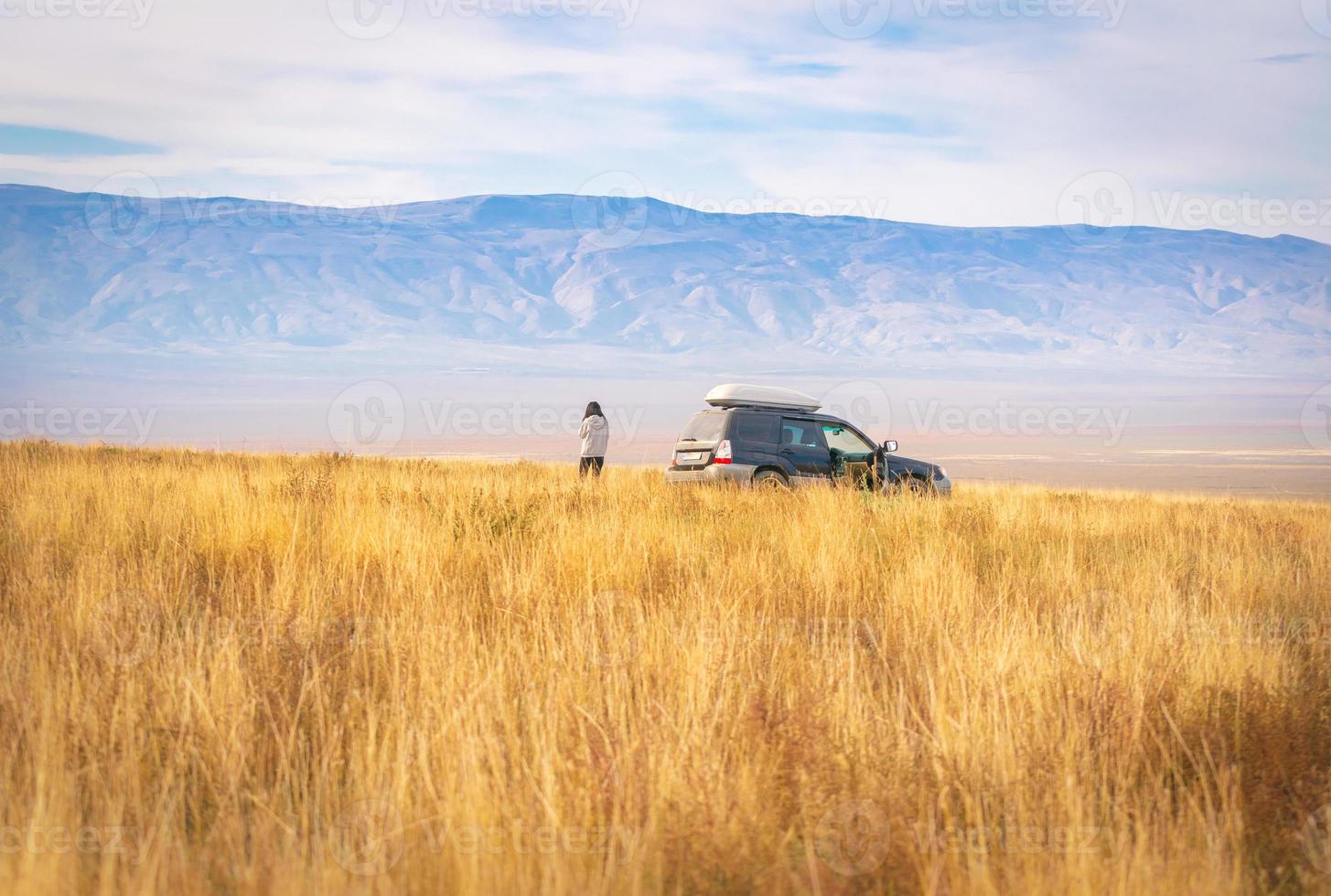 Vista de fondo del hermoso panorama de la pradera de vashlovani con 4wd de pie en medio con una mujer de pie y disfrutar de las vistas.destino de viaje georgia. foto