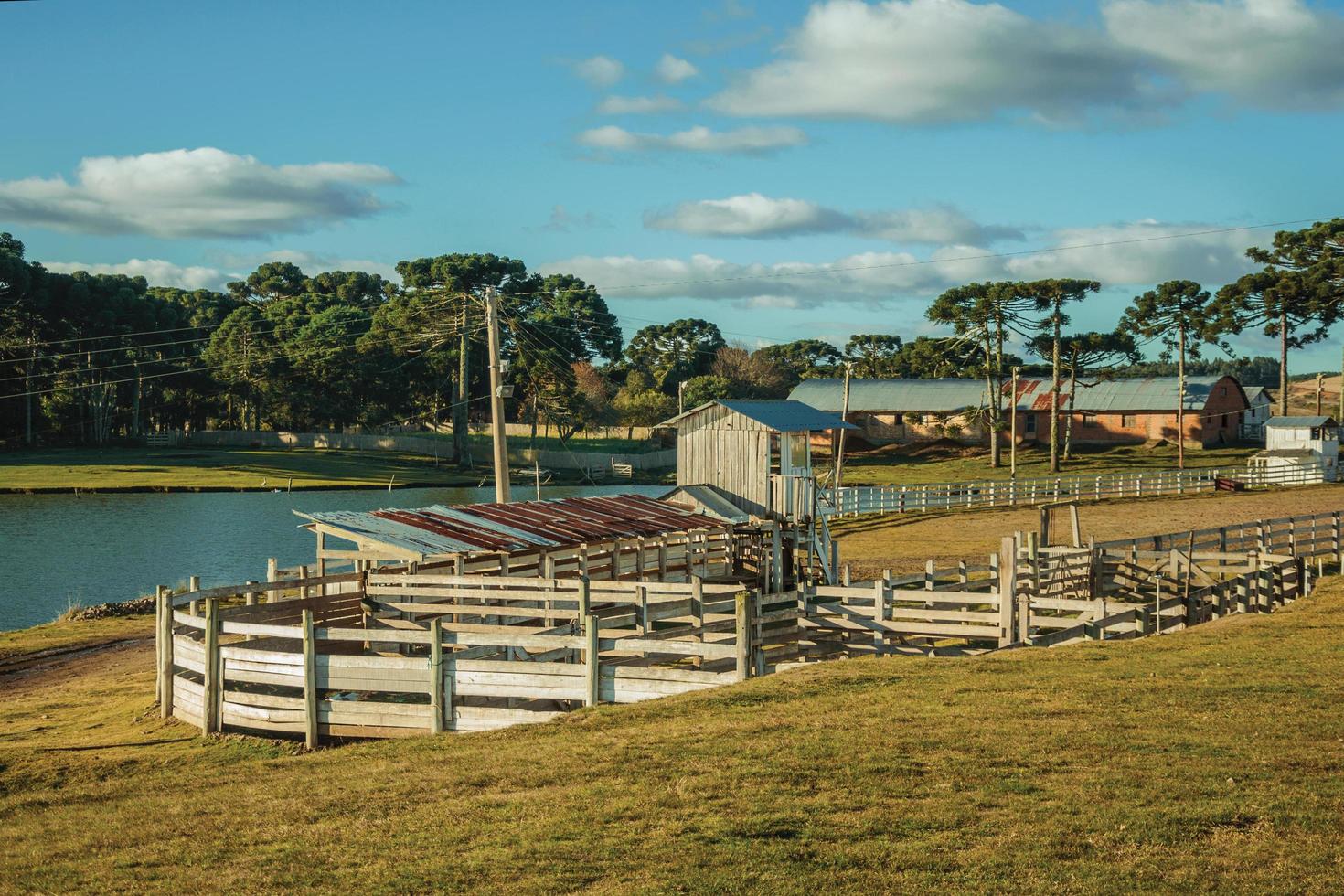 Pretty farm with fences, livestock sheds and blue lake on landscape of rural lowlands called Pampas at Cambara do Sul. A small country town in southern Brazil with amazing natural tourist attractions. photo