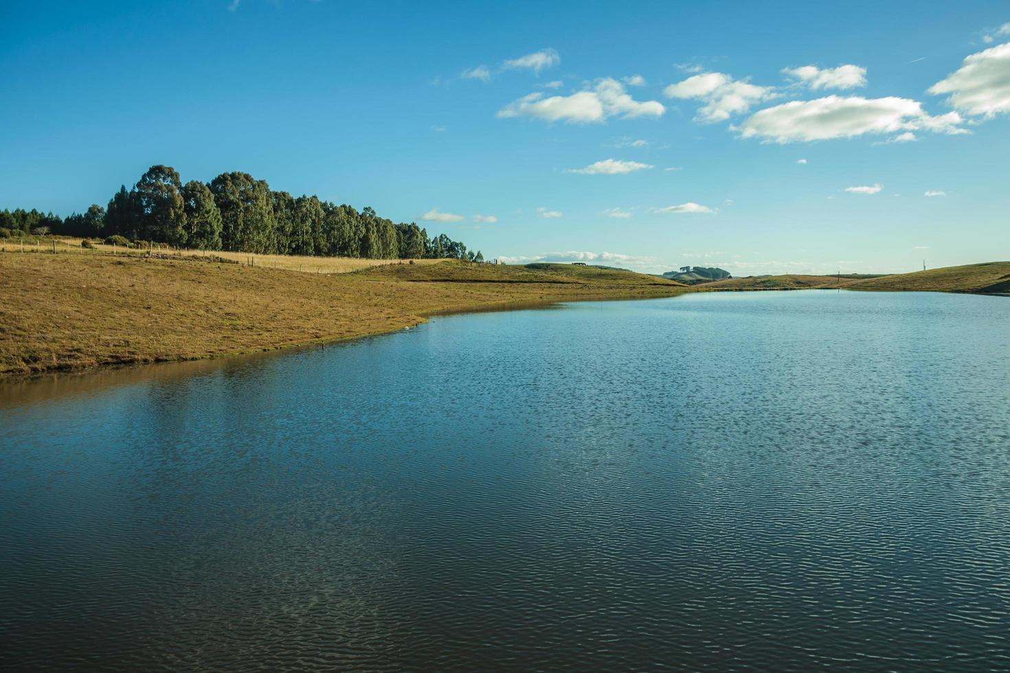 Blue water lake on landscape of rural lowlands called Pampas with dry bushes covering the hills near Cambara do Sul. A small country town in southern Brazil with amazing natural tourist attractions. photo