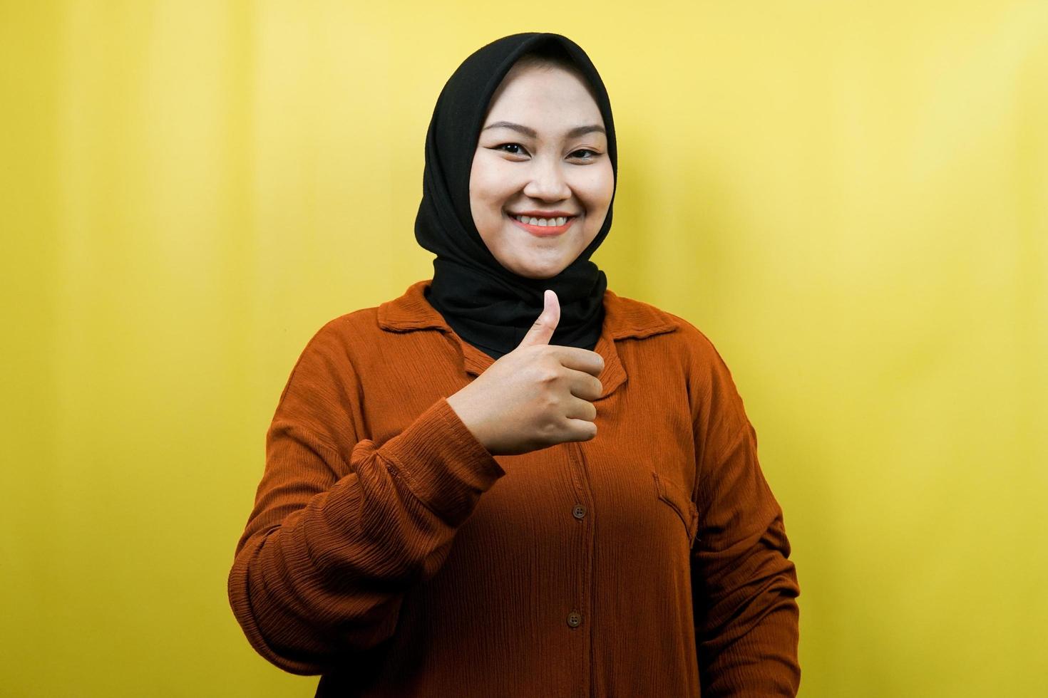 Beautiful young asian muslim woman with thumbs up hand, ok sign, good job, success, congratulations, victory, smiling confident, enthusiastic and cheerful, looking at camera isolated photo